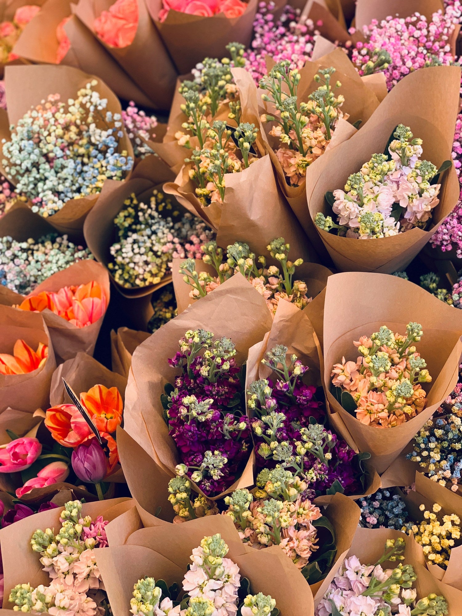 Tiges de fleurs individuelles disposées pour créer un bouquet personnalisé dans un marché aux fleurs rustique.